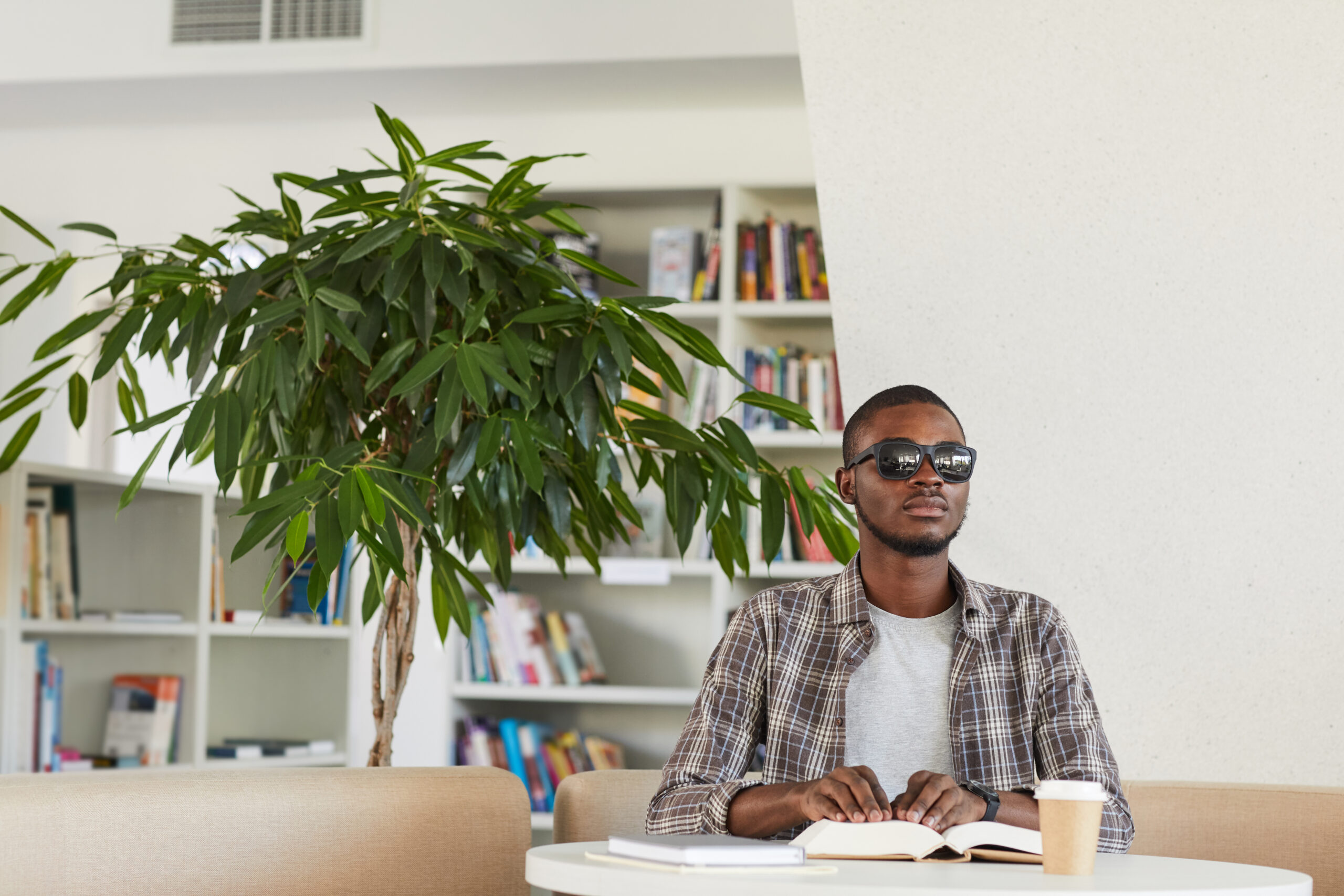 Blind African American Man Reading a Braille Book in Library