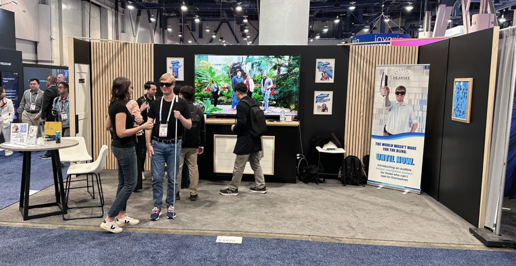 A group of people stand in the Hearsee Mobility booth at the 2024 CES expo in Las Vegas.